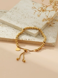 Detail of gold beaded bracelet featuring a heart pendant and adjustable sliding clasp