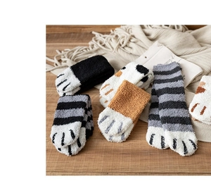 Detailed view of various cute cat paw coral fleece warm socks on a wooden table