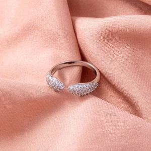 Detailed macro view of open heart zircon ring on soft pink silk fabric background