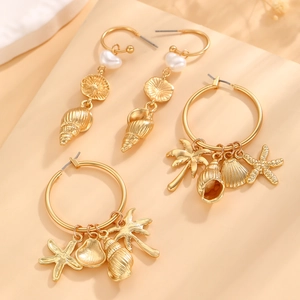 Dettaglio di orecchini dorati con perle, conchiglie e ciondoli a forma di stella marina