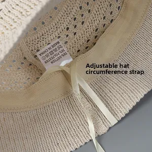 Detail of hollow knit bucket hat featuring adjustable drawstring and cotton fabric label