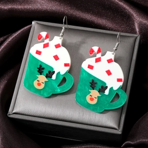 Close-up of Christmas reindeer coffee cup acrylic earrings on a luxury velvet display
