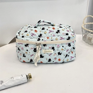 Close-up of quilted blue makeup bag with cartoon cat patterns and stylish logo ribbon