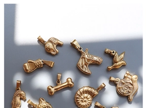 Detailed flat lay of assorted 18K gold plated animal pendants including elephant and horse