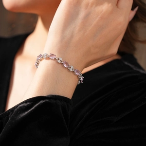Close-up of vintage silver bracelet with pink oval gemstone and clover charms on model's wrist