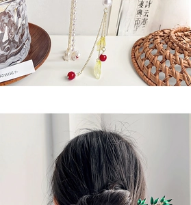 Detailed view of gold tassel hair pin with red beads and pearls in traditional style