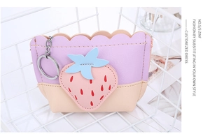 Detail of strawberry coin purse in lavender leather with keychain in white wire basket