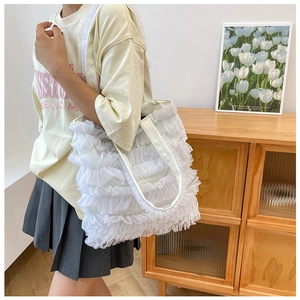 Détail d'un sac cabas blanc à volants en maille avec texture mousseline et bandoulière