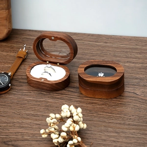 Detail view of oval walnut wood jewelry box with transparent window and white lining