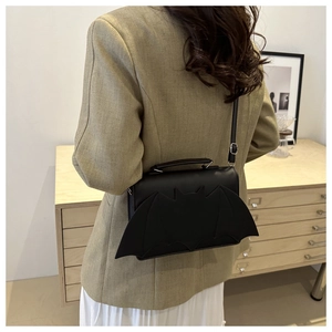 Rear view of a model wearing a black bat-shaped crossbody bag with decorative wings