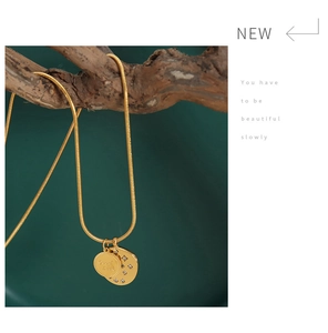 Close-up of golden snake chain with double lucky charms hanging on wooden branches
