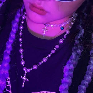 Détail du collier de perles multicouche avec croix en strass sous néon violet
