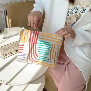 Close-up of striped corduroy makeup bag with metal zipper and minimalist logo label