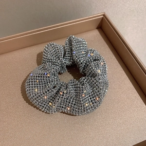 Exaggerated silver scrunchie with sparkling rhinestones on beige jewelry tray