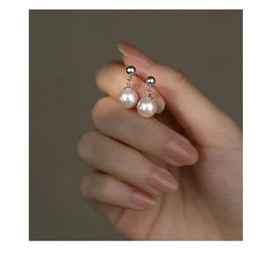 Detail showing a pair of elegant white pearl earrings on a polished silver base
