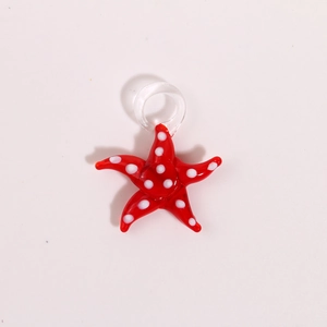 Macro detail of a red glass starfish pendant with white polka dots and a clear glass loop