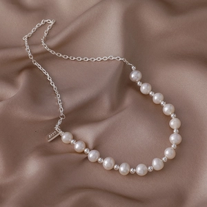 Primer plano de un collar de perlas de agua dulce vintage con colgante LOVE grabado en seda