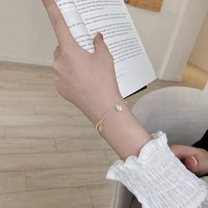 Detail of S925 silver beaded bracelet with baroque pearl and gold pendant held by model
