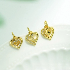 Detail of 18K gold plated heart charms with cubic zirconia on white porcelain