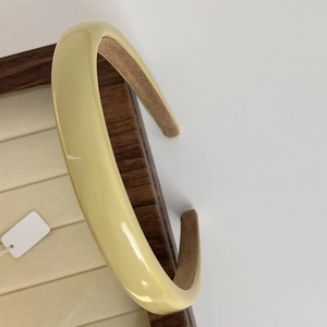 Detail of pale yellow headband featuring glossy finish and brown non-slip velvet lining