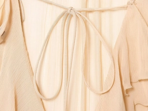 Detailed close-up of apricot chiffon shirt featuring tie-up straps and pleated texture