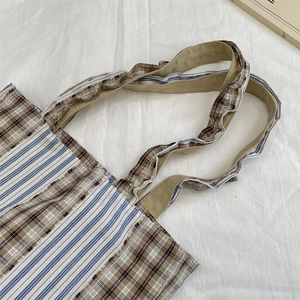 Detail of vintage patchwork tote bag with plaid patterns and ruffled shoulder strap texture