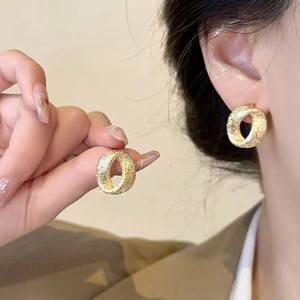 Detail of vintage gold textured hoop earrings showing matte finish and wearing effect