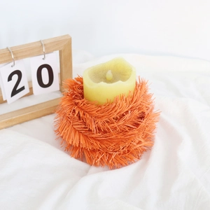 Vibrant orange pine needle candle ring surrounding a warm yellow pillar candle decoration