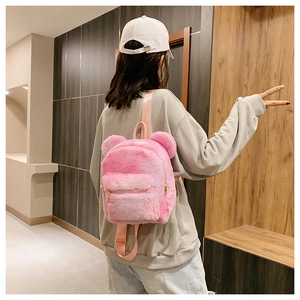 Pink plush backpack with bear ears shown on model back in a modern interior setting