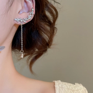 Detailed view of silver ear cuff with rhinestone teardrop tassel on model ear