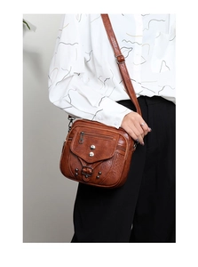 Détail du sac bandoulière marron vintage en cuir souple avec rivets et multiples zips