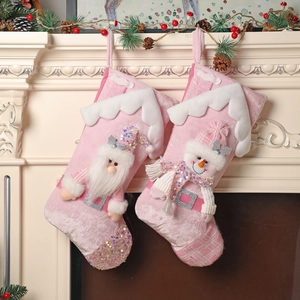 Pink sequined Christmas stockings with Santa and snowman hanging on a festive mantel