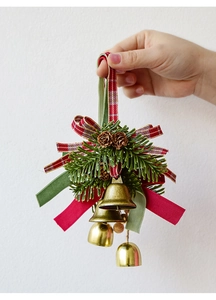Close-up of golden Christmas bells with pine cones, needles and red green ribbons