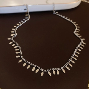 Detailed view of a silver choker necklace featuring metallic leaf pendants on a dark base