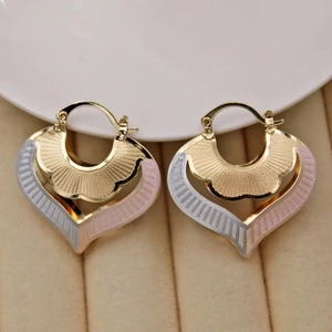 Detail of three-tone hoop earrings featuring fan-shaped heart motifs and wavy textures