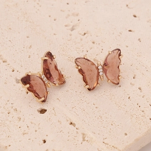 Macro detail of butterfly stud earrings with rose gold base and amber brown wings