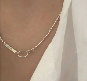 Close-up of S925 silver beaded necklace with an engraved metal pendant on the neck