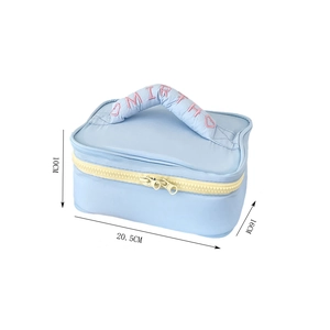 Detail showing dimensions of blue quilted makeup bag with yellow dual zippers and embroidery