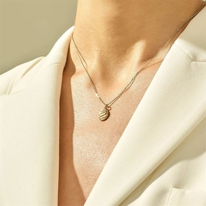 Minimalist gold stainless steel necklace featuring a textured oval pendant on a model