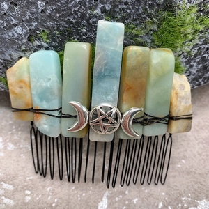 Detail of natural crystal hair comb with silver moon and star charms on mossy ground