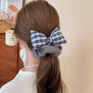 Detailed close-up of navy blue plaid and grey fabric bow scrunchie for ponytails