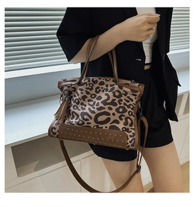 Close-up of leopard print shoulder bag with gold rivets and decorative brown fringe