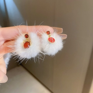 Detail of plush white ball earrings with red gemstones and festive gold Fu character