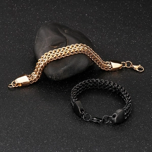 Close-up of gold and black double-row Franco chain bracelets on textured dark stones