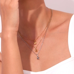 Macro view of triple-layered 18K gold and silver necklaces with letter pendants