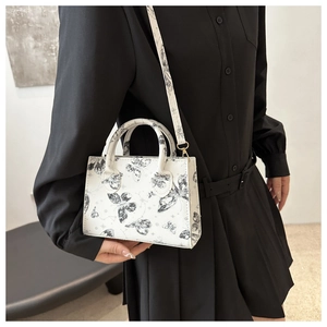 Detail of white butterfly print handbag with golden metal buckles and detachable strap