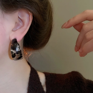 Detailed view of resin leopard print C-shape hoop earrings on a model's ear