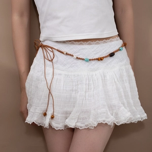 Détail d'une jupe en dentelle blanche avec ceinture bohème faite main à perles et glands