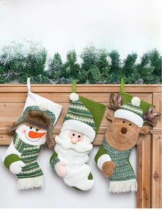 Three knitted Christmas stockings with Santa, Snowman and Reindeer motifs on a fireplace