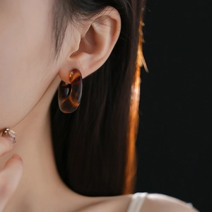 Close-up of leopard print resin C-shaped earring with tortoise shell texture on model